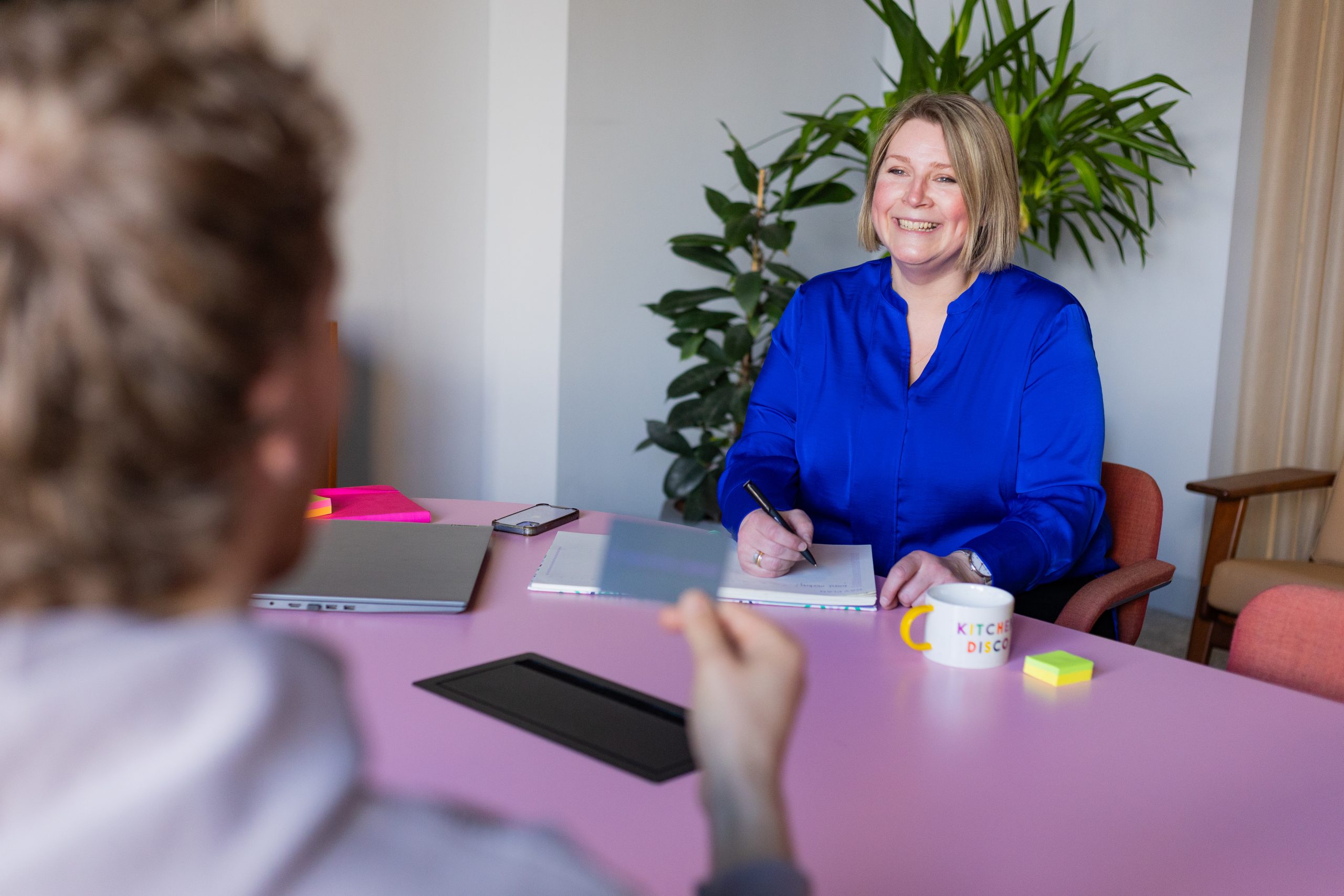 Jacqui Kemp and one other collaborating at a pink table in a business meeting